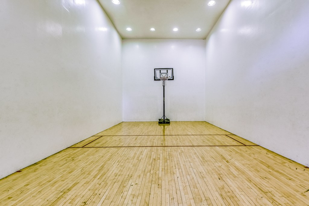 a white room with a wooden floor and a basketball hoop