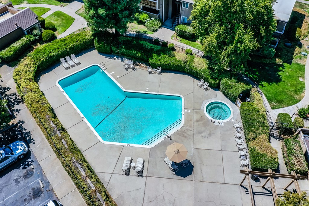 an aerial view of a swimming pool with a hot tub and lounge chairs in front of a