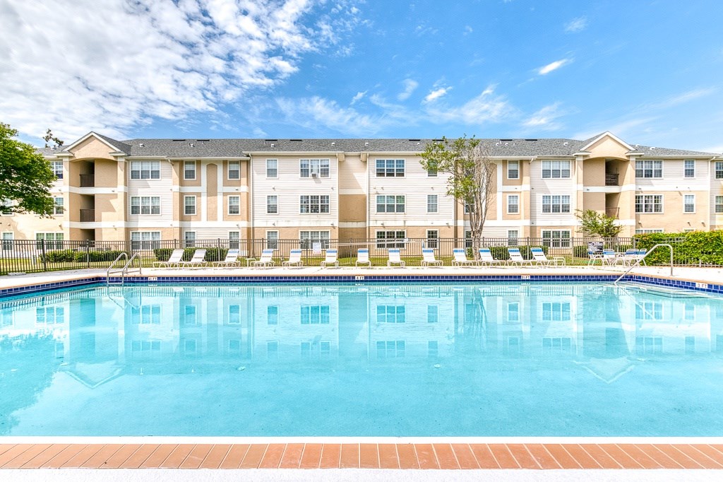 A large apartment complex with a pool in front.