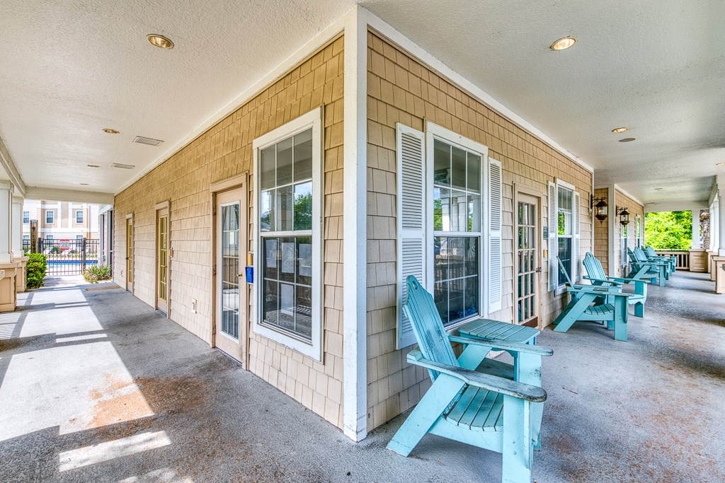 A sunny day at the beach with chairs and a house.