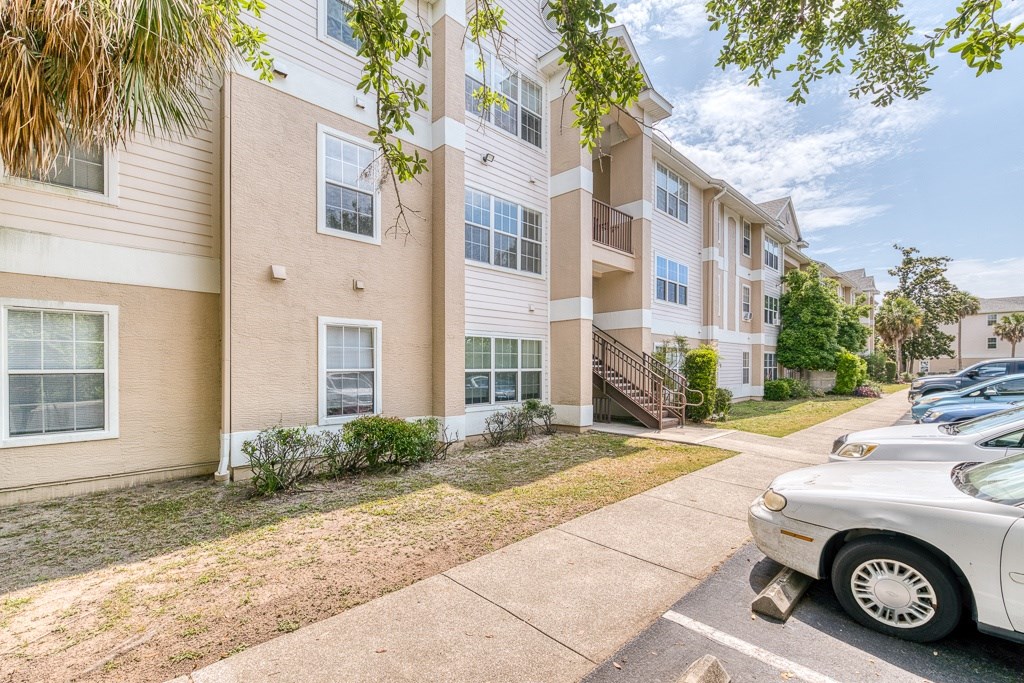 A white car is parked on the side of a street in front of a building.
