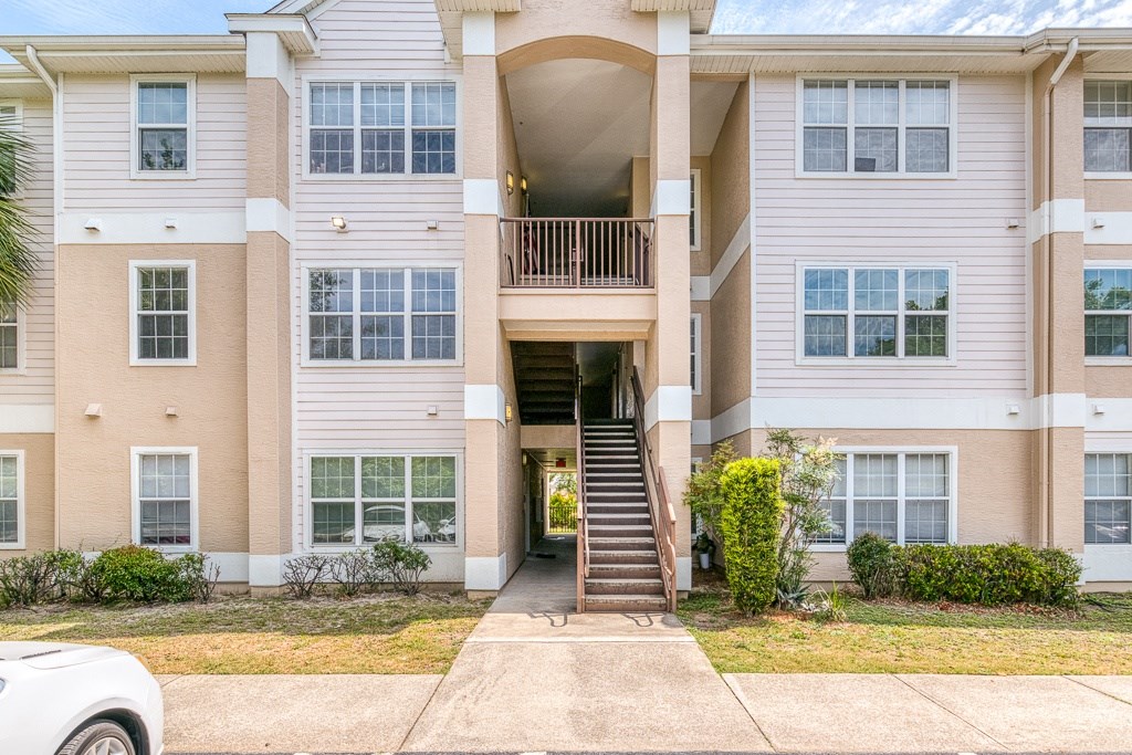 A white car is parked in front of a two-story apartment building.