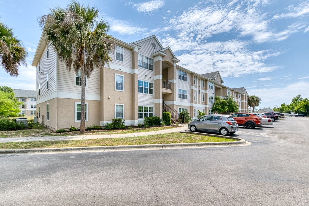 A row of apartment buildings with a parking lot in front.