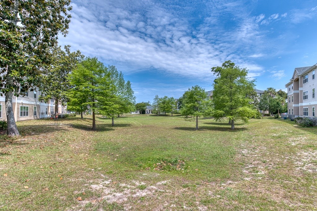 A large grassy field with trees and a building in the background.