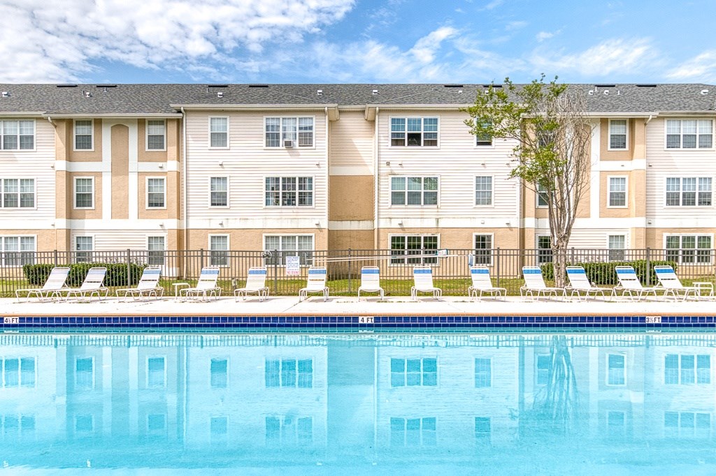 A large apartment complex with a pool in front.