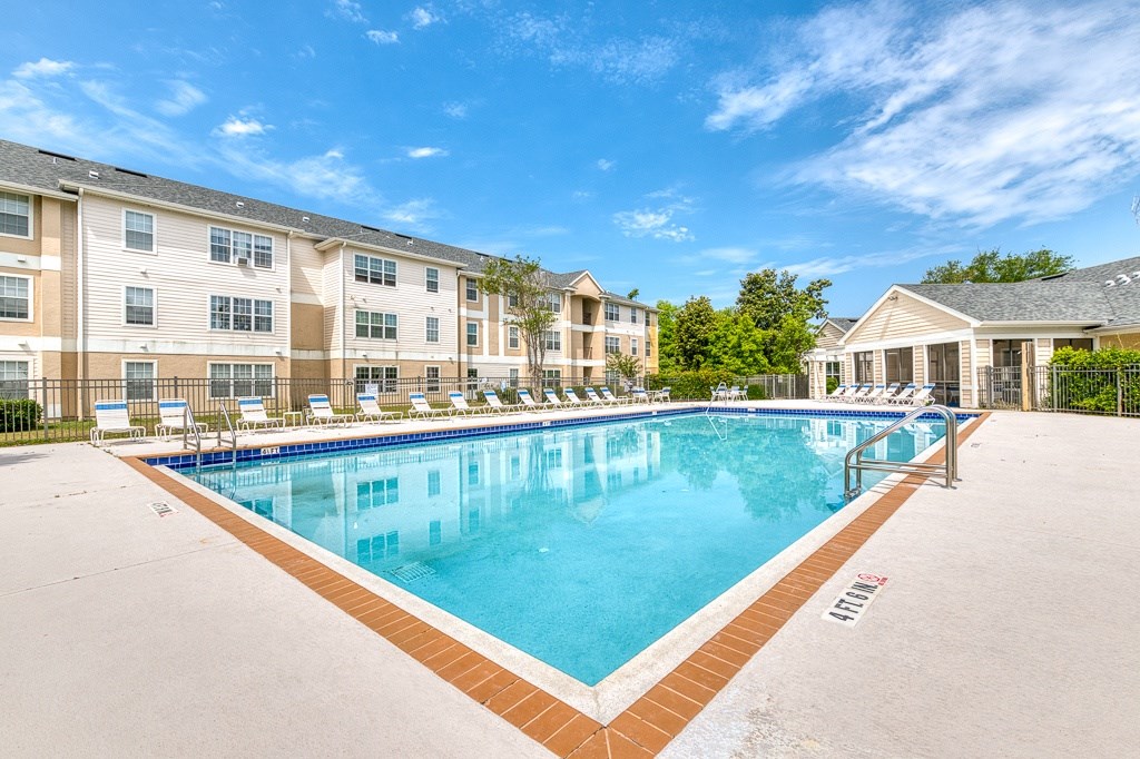 A large swimming pool in front of apartment buildings.