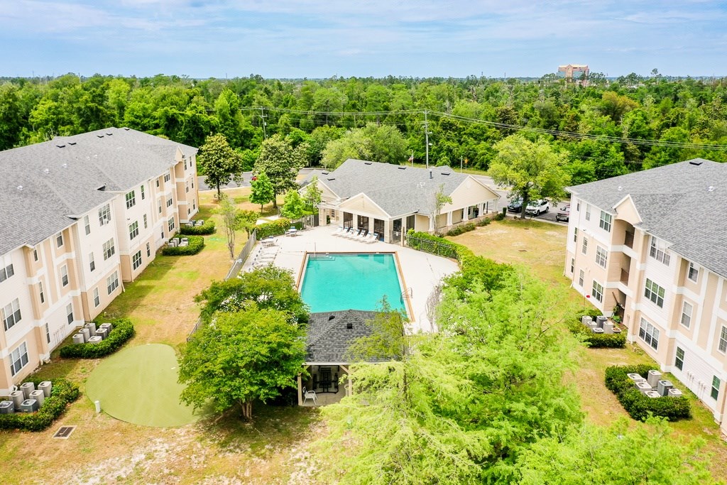 An aerial view of apartment buildings with a pool in the middle.