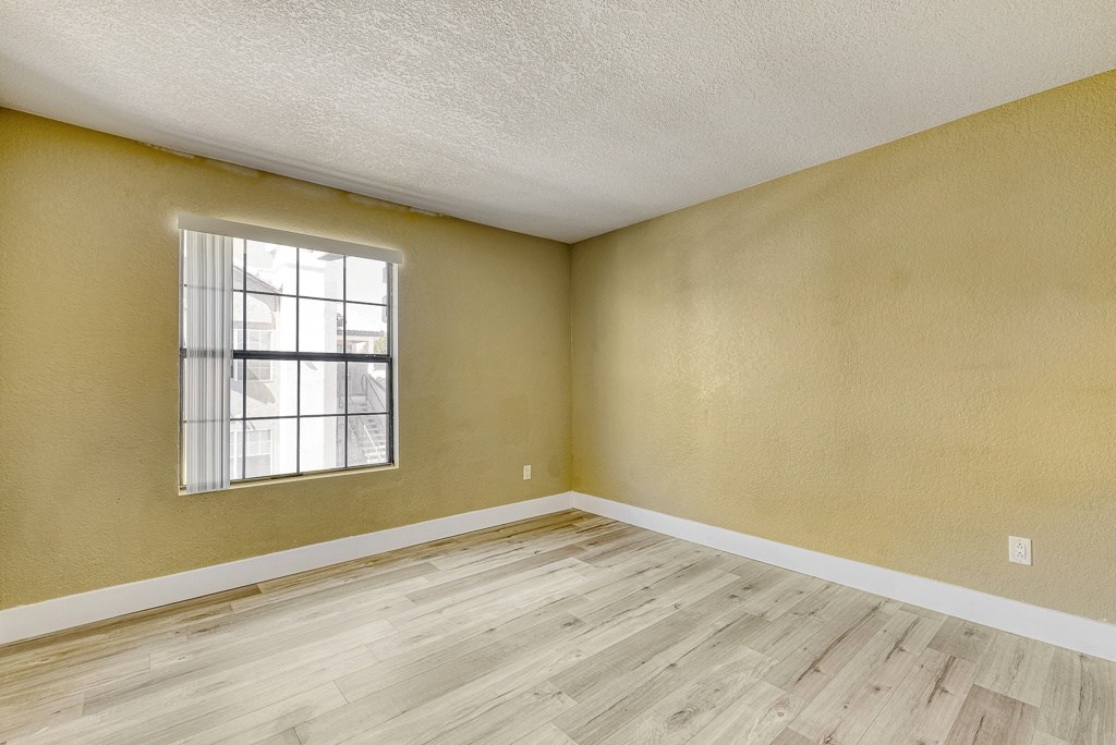 an empty living room with wood floors and a window