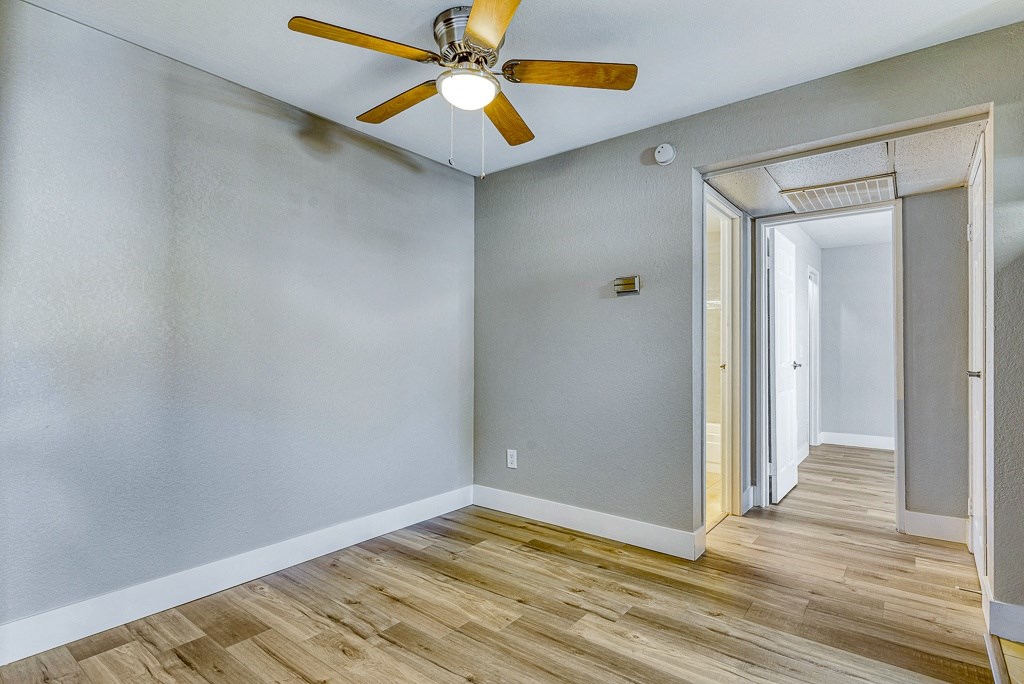 an empty room with wood floors and a ceiling fan