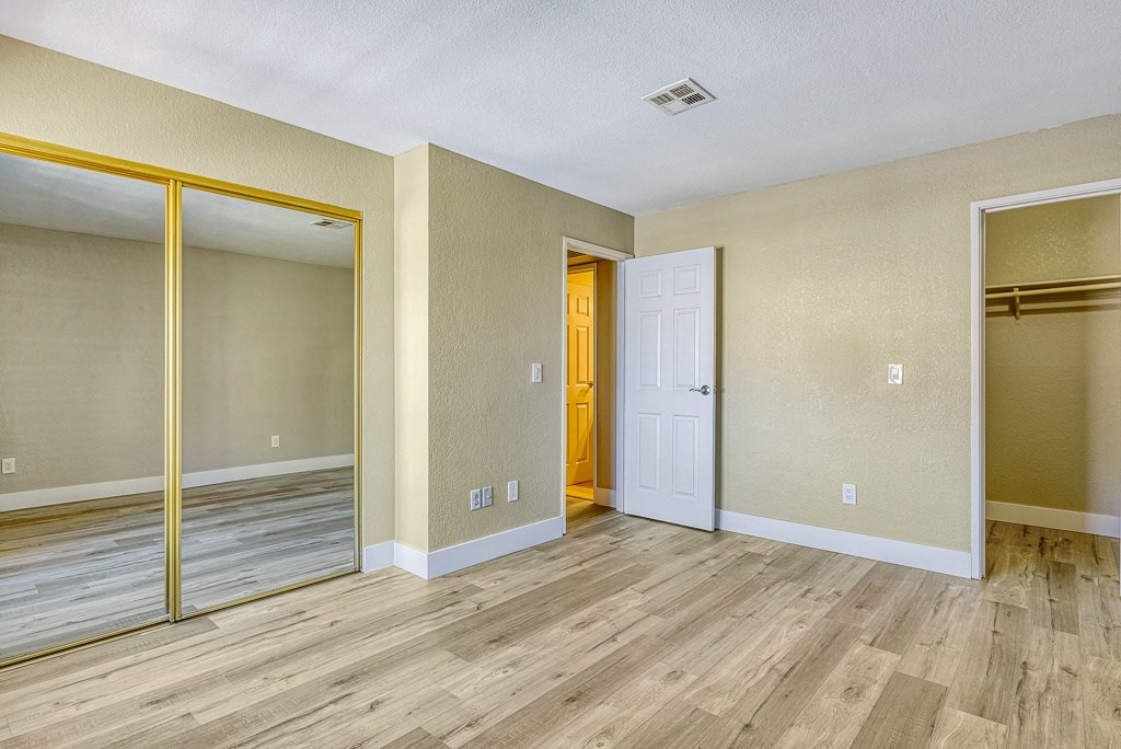 the living room of an empty apartment with wood floors and a door to the hallway