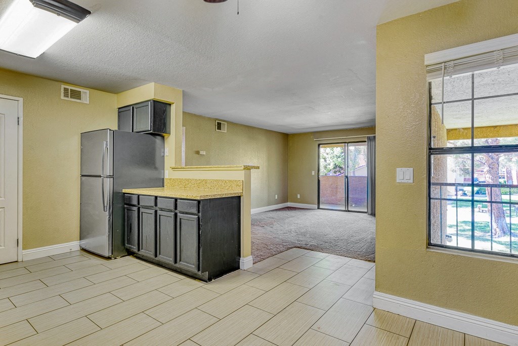 an empty kitchen and living room with a refrigerator