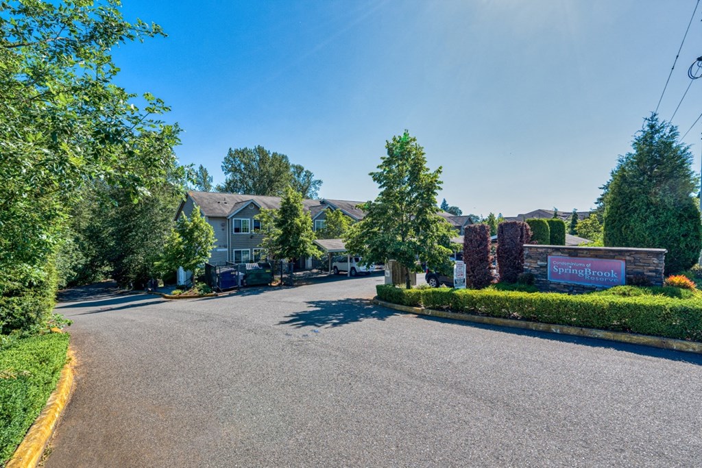 a street view of a house with a driveway and trees
