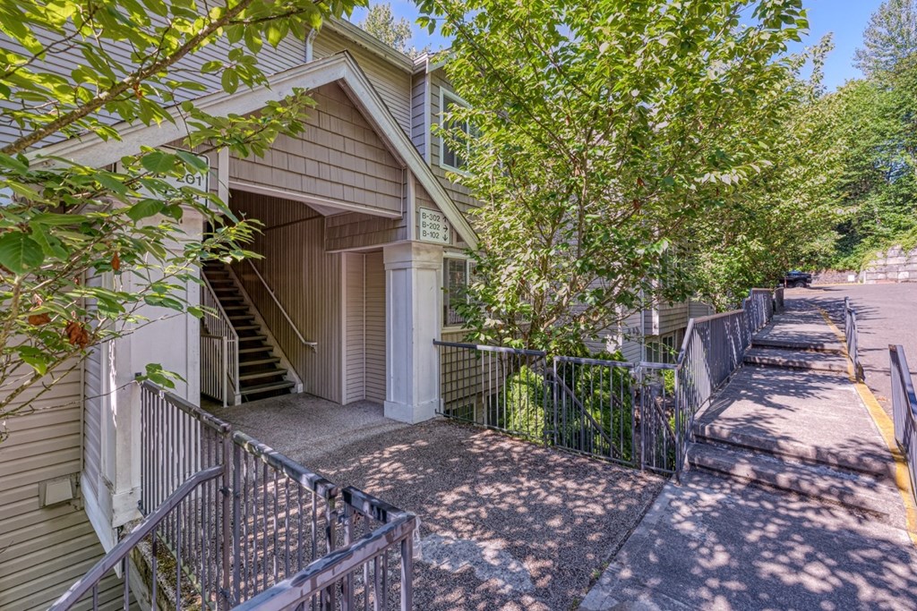 stairs leading up to a house with a sidewalk and trees