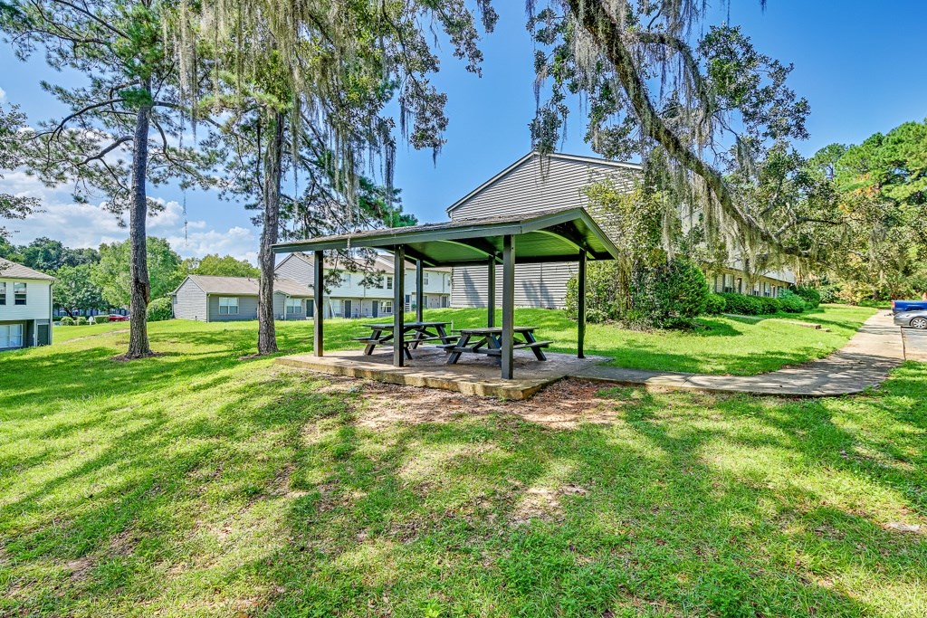 A picnic table is situated under a pavilion in a grassy area.