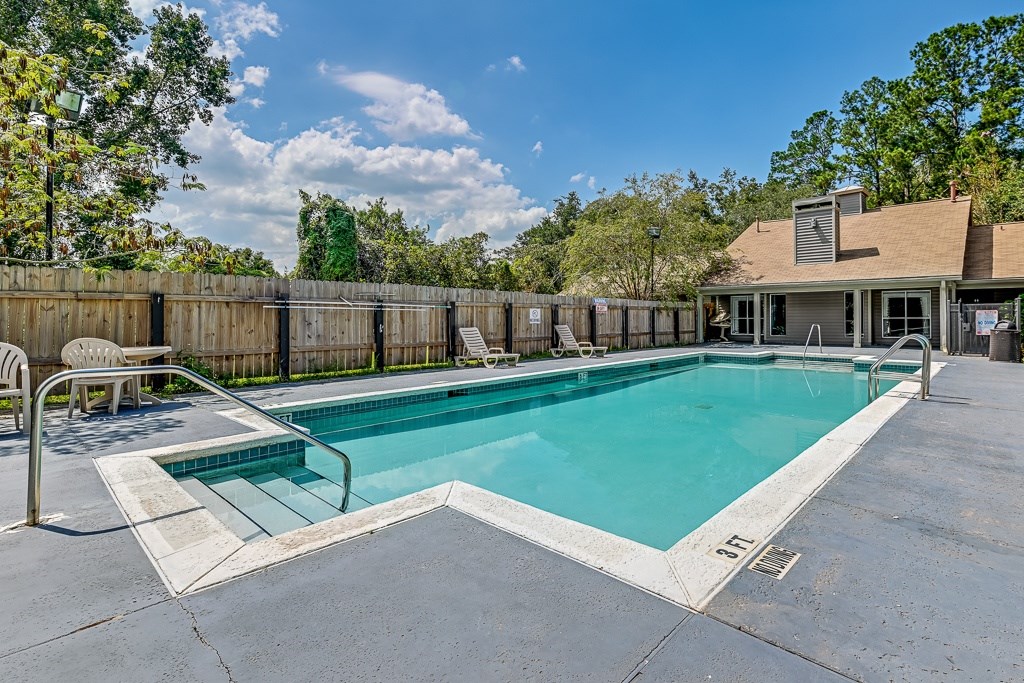 A large outdoor swimming pool surrounded by a wooden fence.