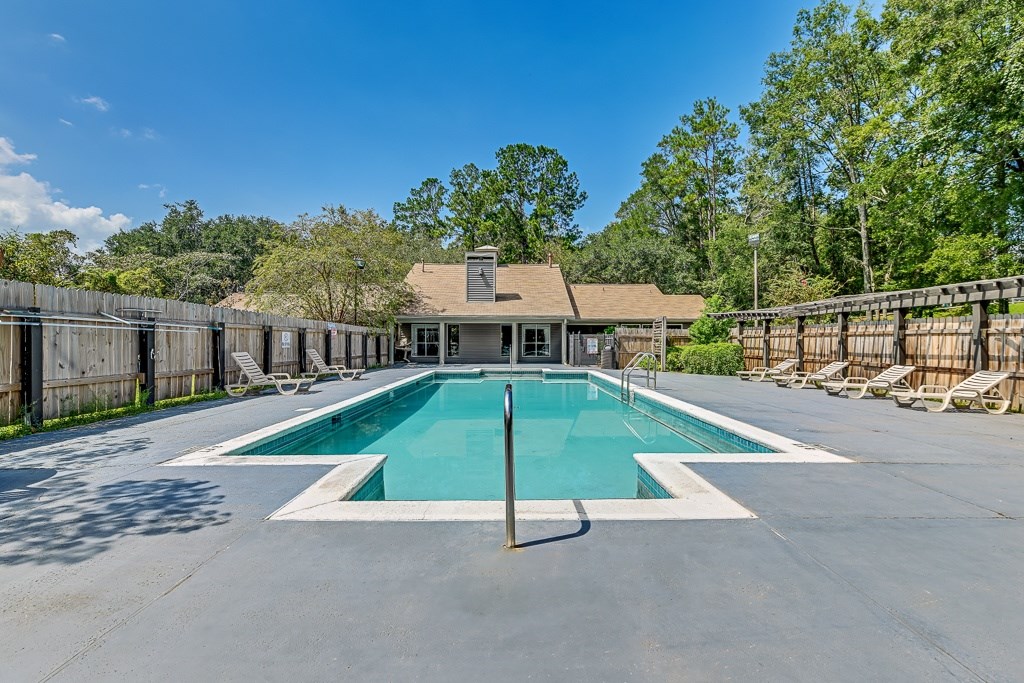 A large outdoor swimming pool surrounded by a wooden fence.