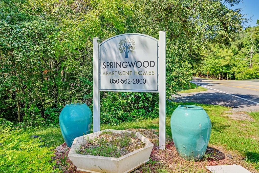 Springwood Apartment Homes sign with a phone number and two vases.