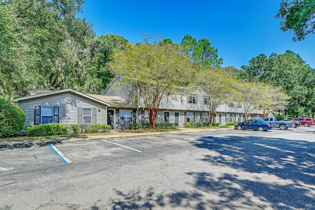 A parking lot with a building and trees in the background.