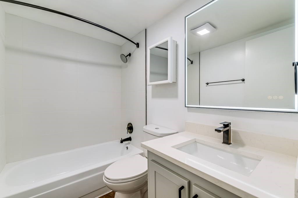 A white bathroom with a toilet, sink, and bathtub.
