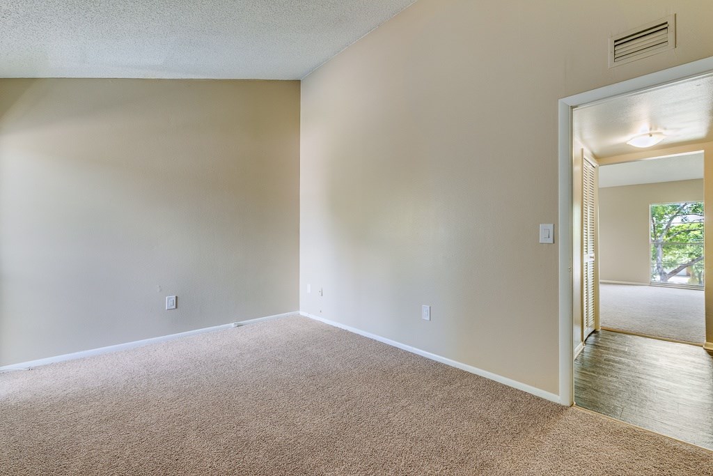 A room with a carpeted floor and a door leading to a balcony.