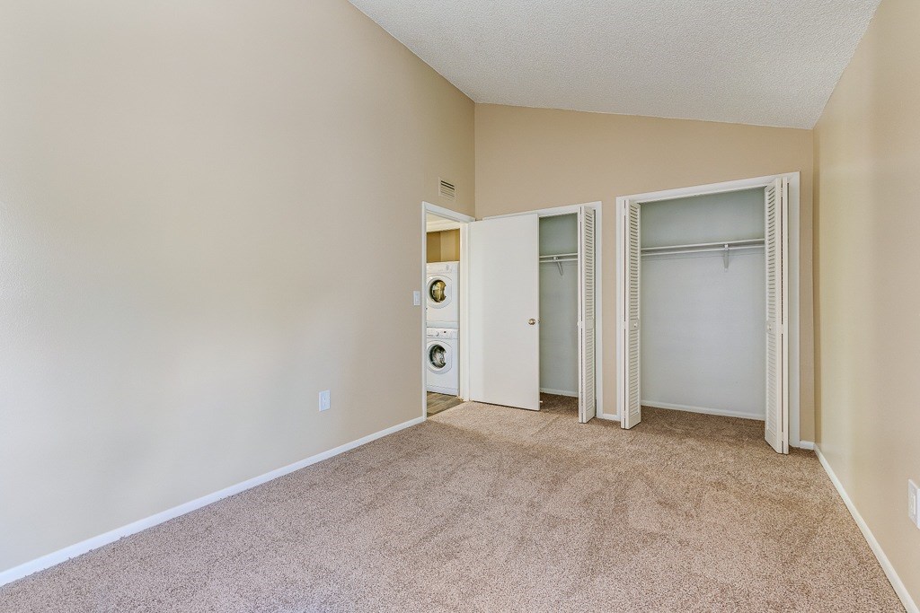 A room with a carpeted floor and two open doors.