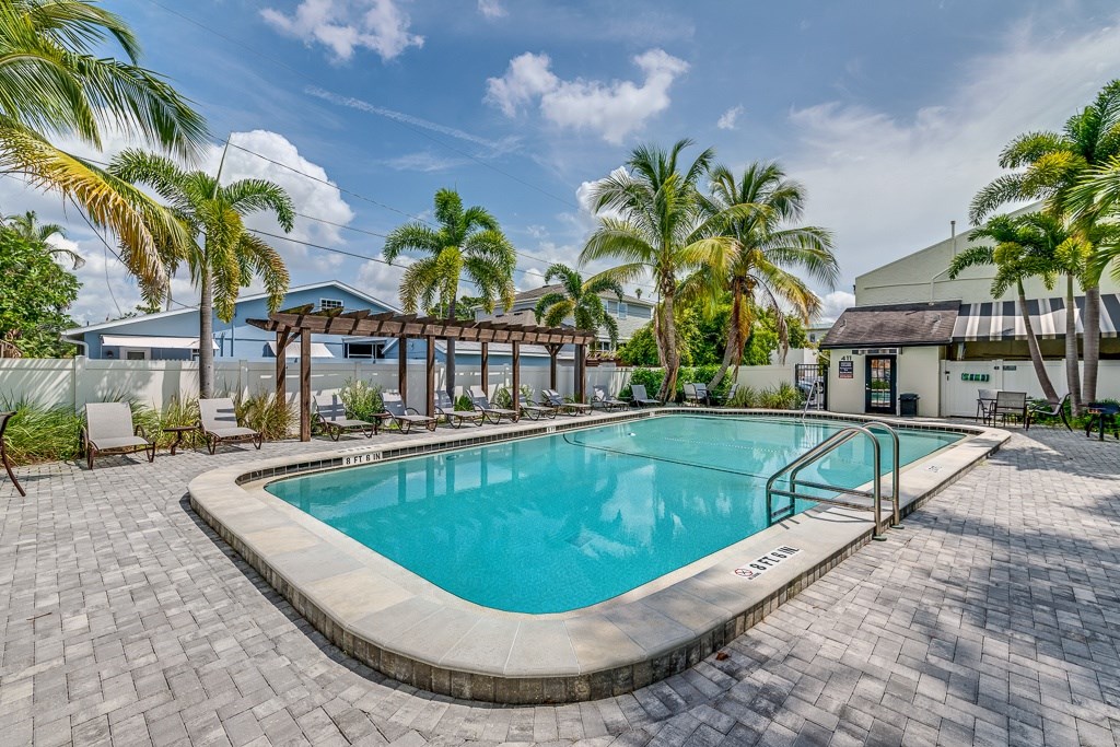 A pool surrounded by palm trees and a building in the background.