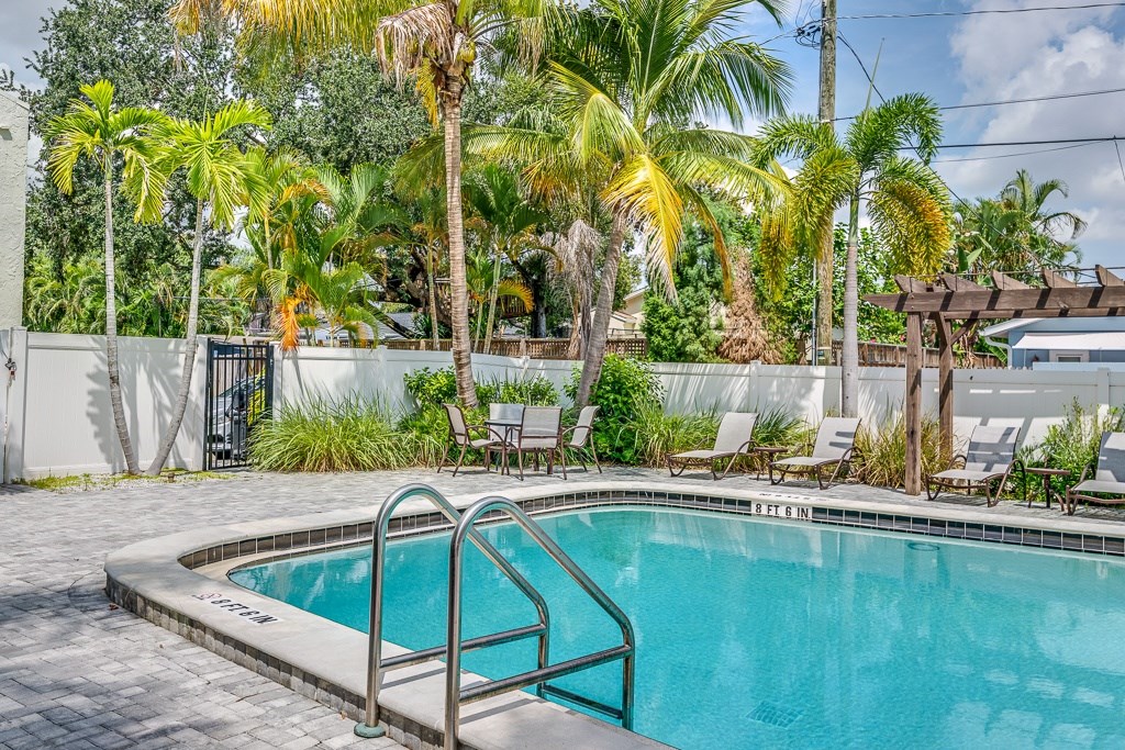 A pool surrounded by palm trees and lounge chairs.