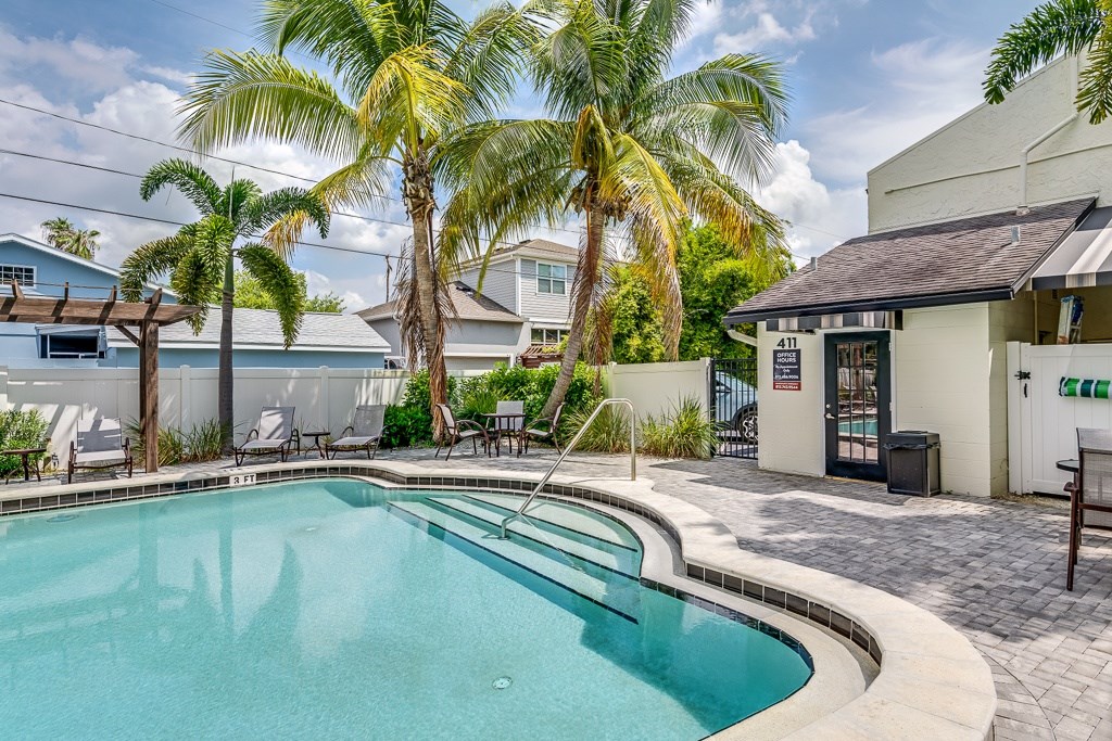 A pool surrounded by palm trees and a building with a sign that says "ALL".