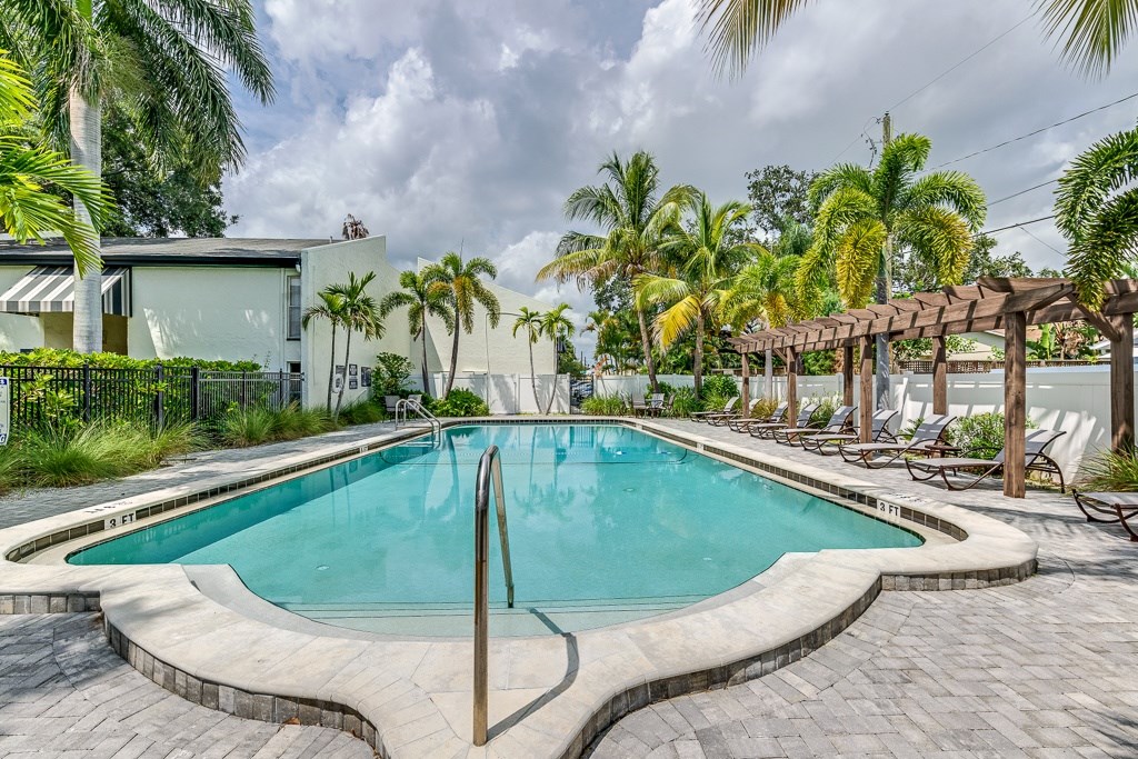 A swimming pool surrounded by palm trees and lounge chairs.