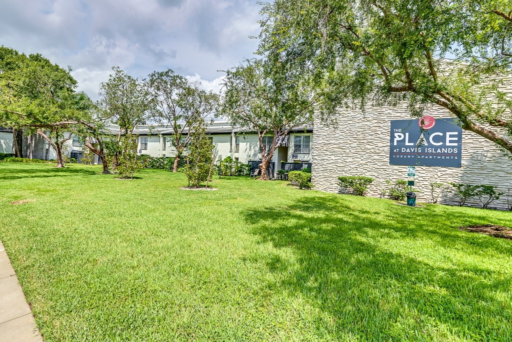 A grassy area in front of a building with a sign that says "PLACE".