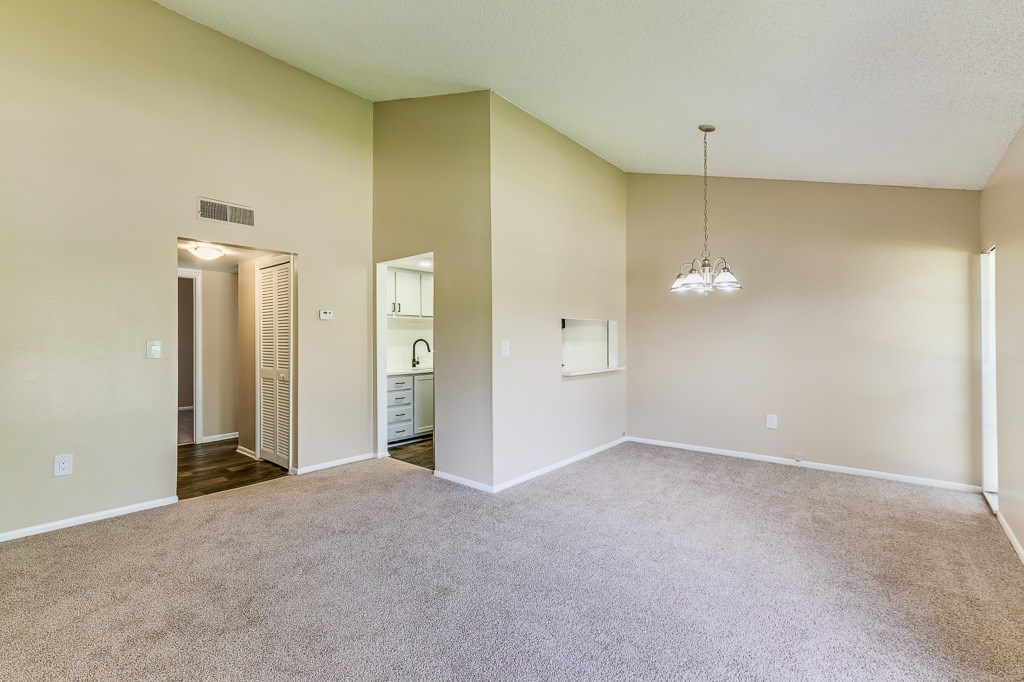 A spacious room with a carpeted floor and a hanging light fixture.