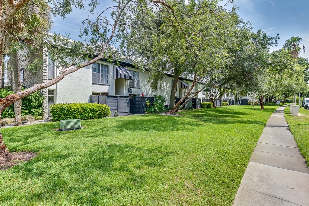 A tree in front of a building with a green lawn.