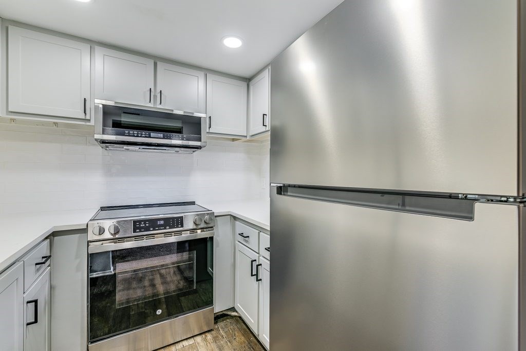 A modern kitchen with stainless steel appliances and white cabinets.