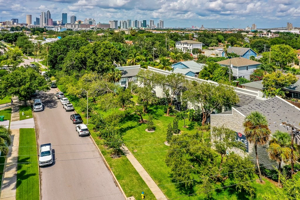 A suburban street with cars parked on the side and a city skyline in the distance.