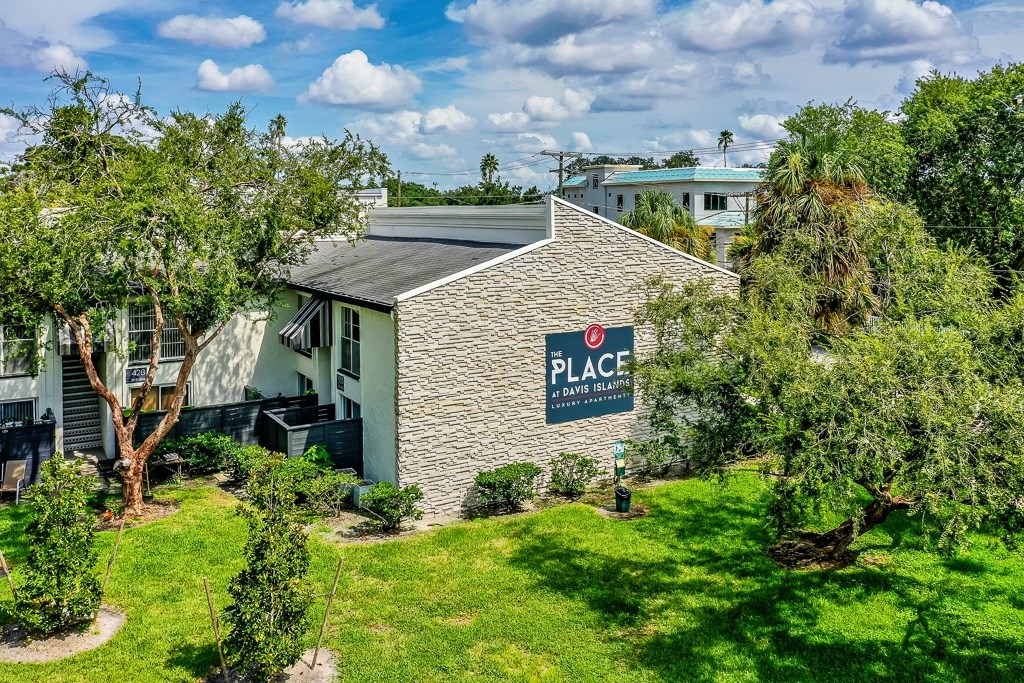 A building with a sign that says "PLACE" is surrounded by greenery.