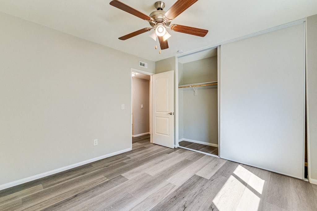 A room with a ceiling fan and a doorway leading to another room.