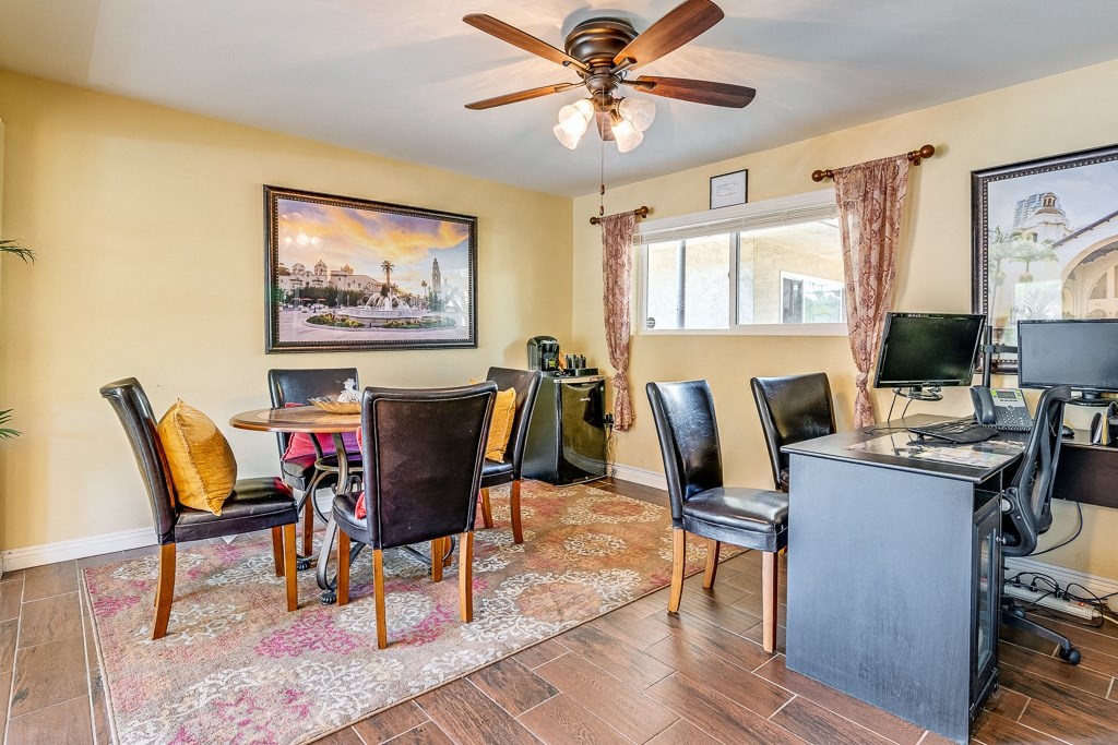A room with a ceiling fan and a painting on the wall.