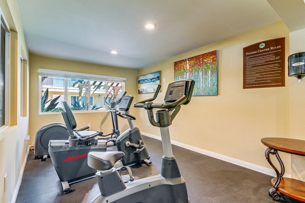 A gym room with exercise equipment and a wooden table.