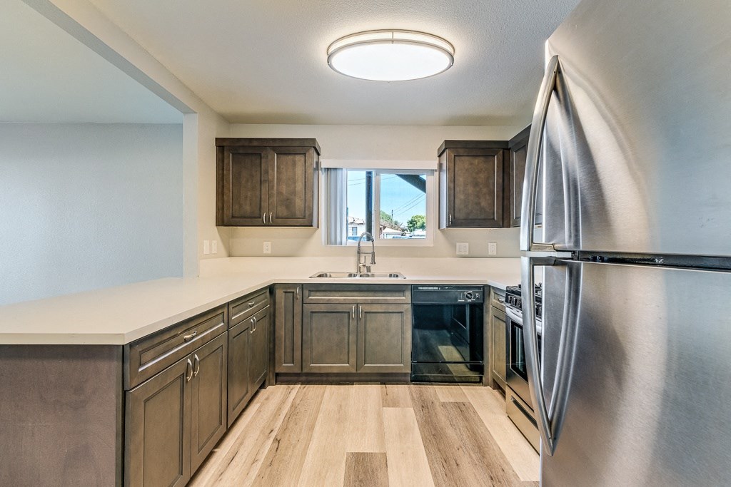 A kitchen with a stainless steel refrigerator and wooden cabinets.