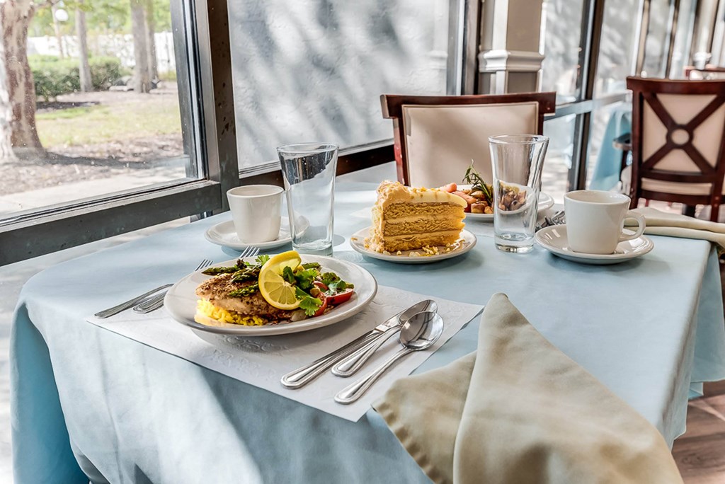 a table with a blue table cloth with a plate of food and a piece of cake on
