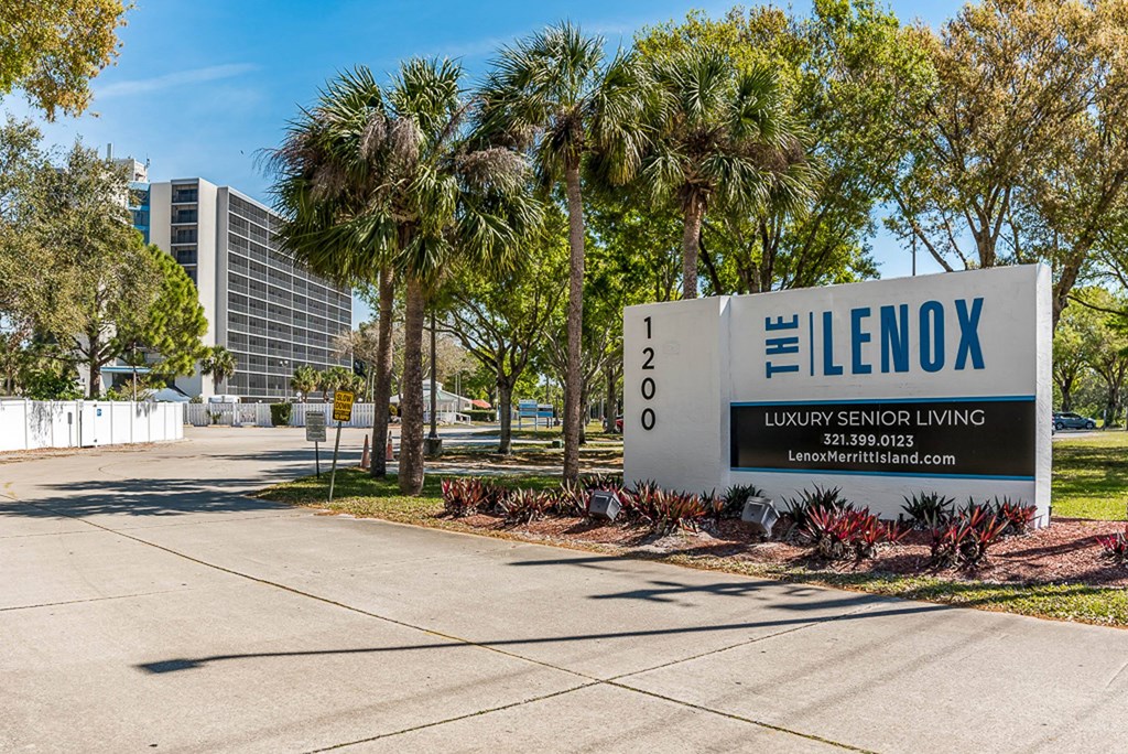 a sign that says the lenox at the entrance to a building with palm trees in the
