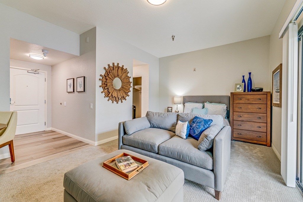A living room with a grey couch and a wooden dresser.