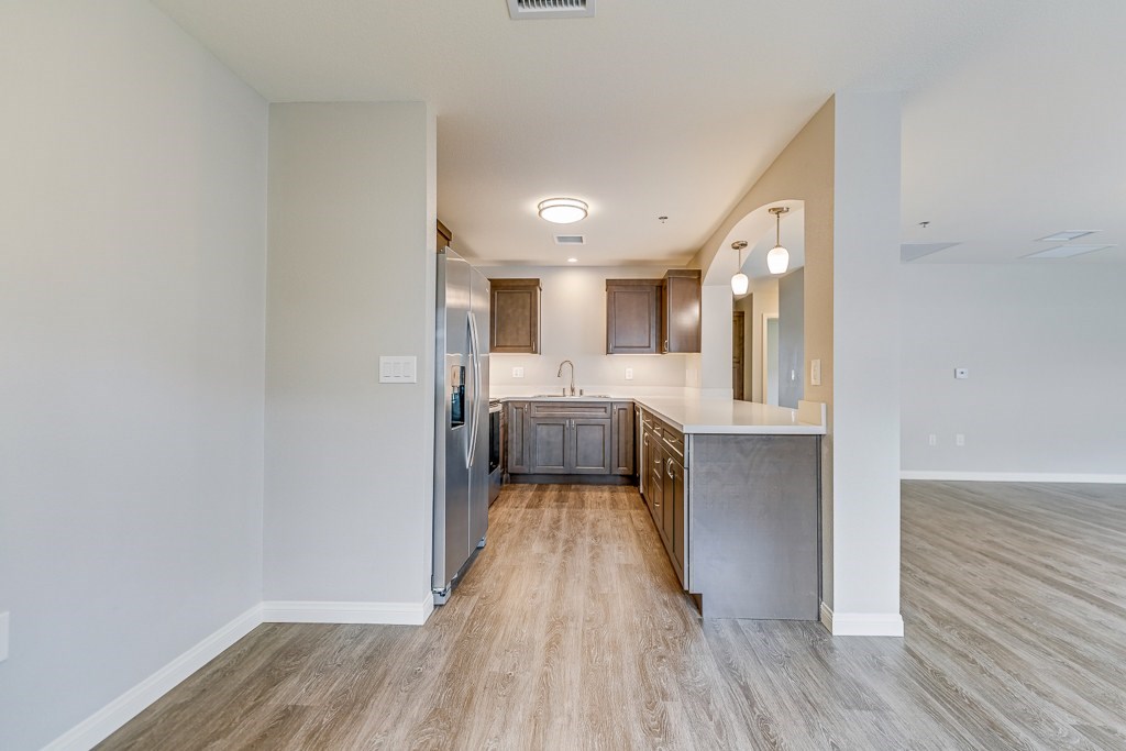 A kitchen with a refrigerator, cabinets, and a countertop.