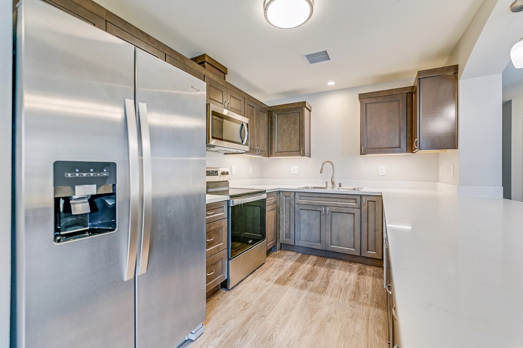 A modern kitchen with a stainless steel refrigerator and wooden cabinets.