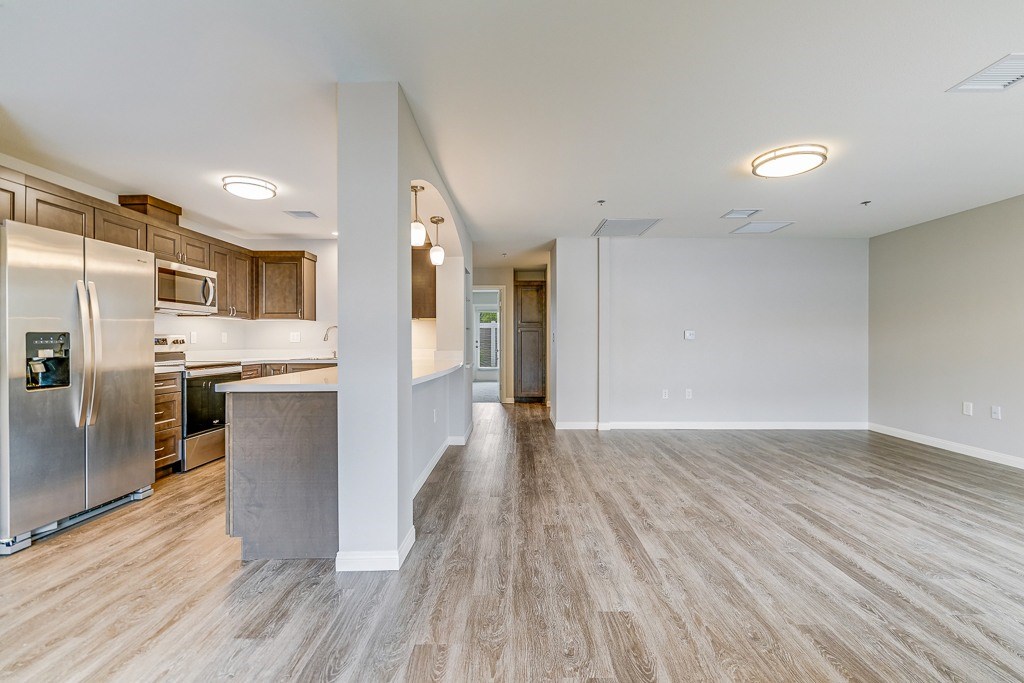 A spacious kitchen with stainless steel appliances and wooden flooring.