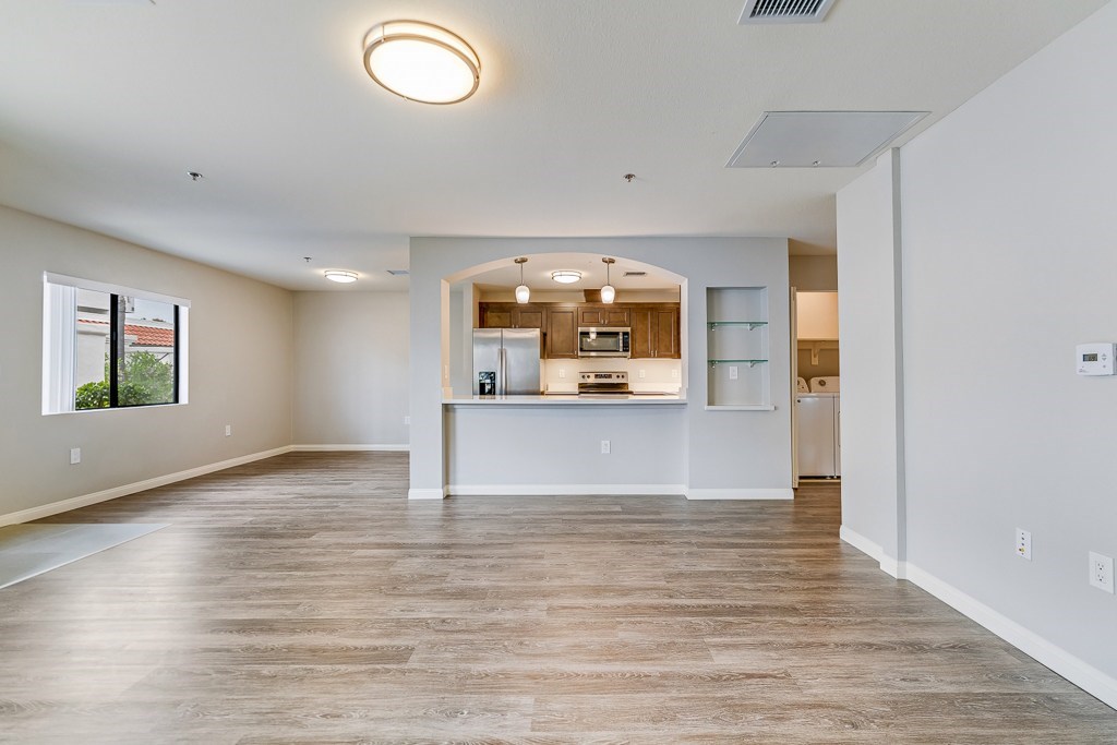 A spacious kitchen with a refrigerator, microwave, and oven, with a bar area in the middle.