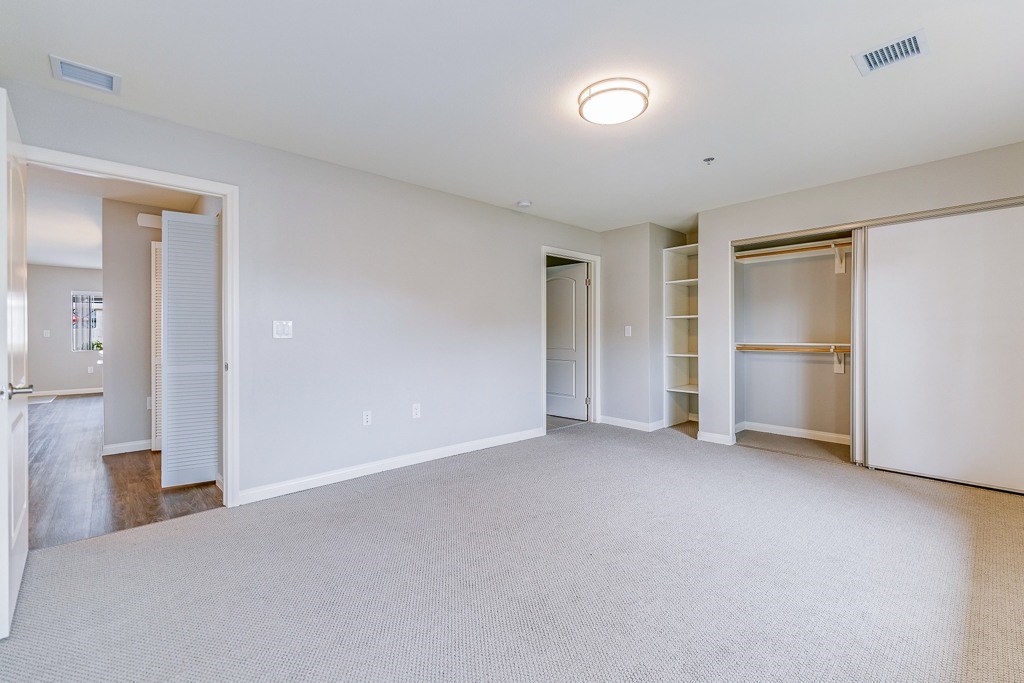 A spacious, empty room with white walls and carpeted floor.