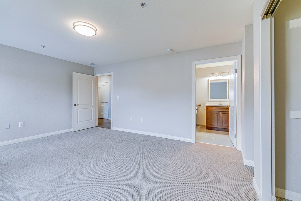 A large empty room with a carpeted floor and a doorway leading to another room.