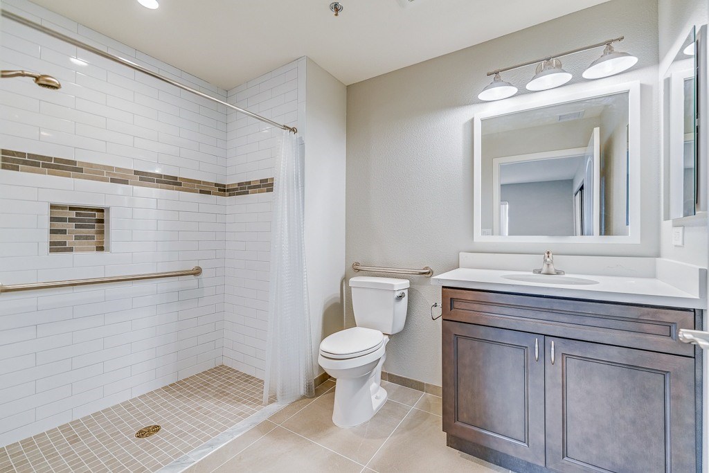 A white toilet sits in a bathroom with a white shower curtain.