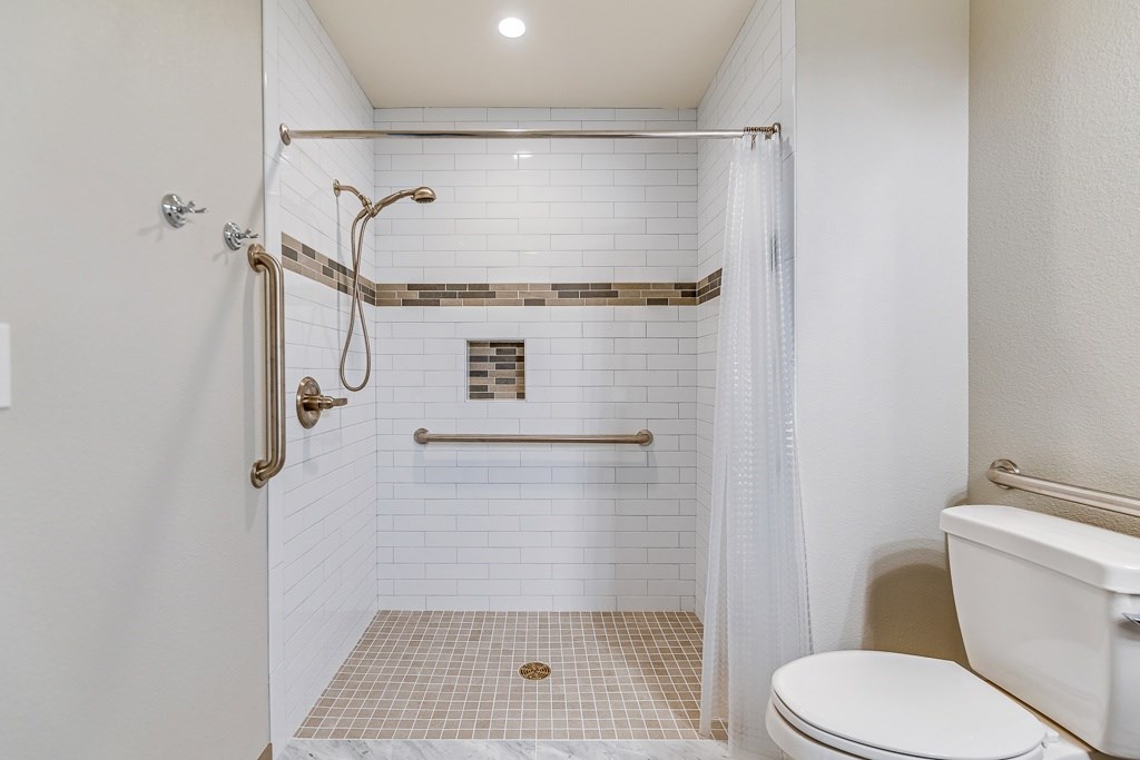 A white bathroom with a toilet, sink, and shower.